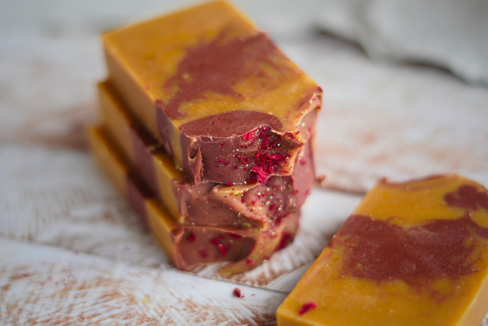 Handgesiedete Kürbisseife mit Patchouli, rotbrauner Marmorierung und Glitzer, dekoriert mit Granatapfelblüten